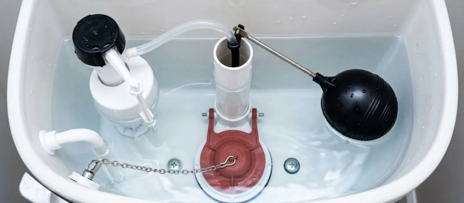 Toilet tank interior with black float ball and chain flapper